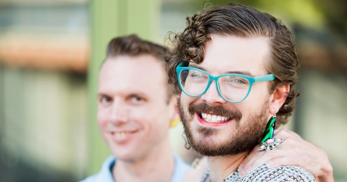 Photo of two young people embracing and looking at camera