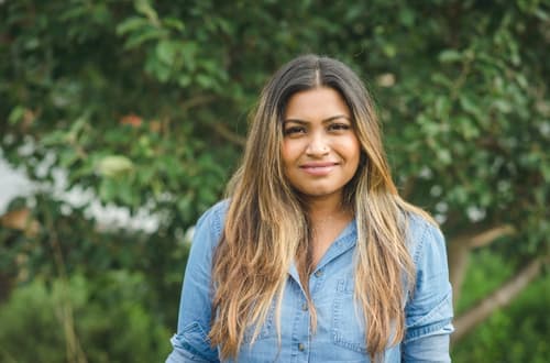 Woman smiling at camera standing in front of a tree