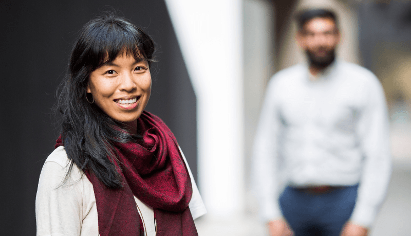 Young woman looking to camera, man in background