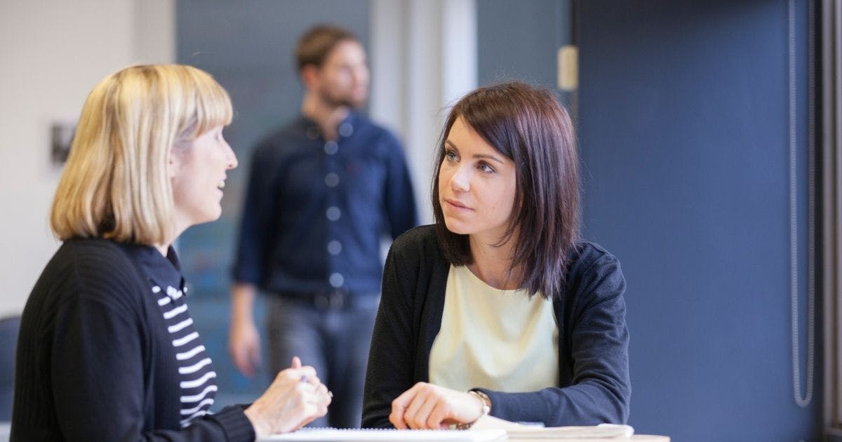 Photo of two women talking in an office environment
