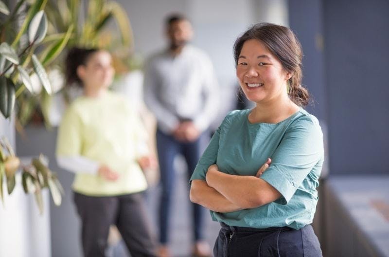 Photo of woman smiling in office with people in the background